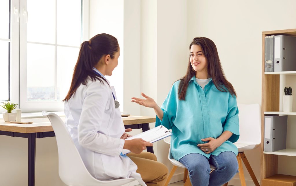 gestante de camisa azul sentada conversando com sua obstetra  de jaleco branco